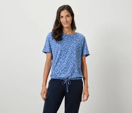 Femme portant un t-shirt bleu à motifs et un pantalon bleu marine.