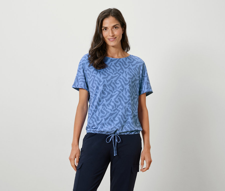 Femme portant un t-shirt bleu à motifs et un pantalon bleu marine.
