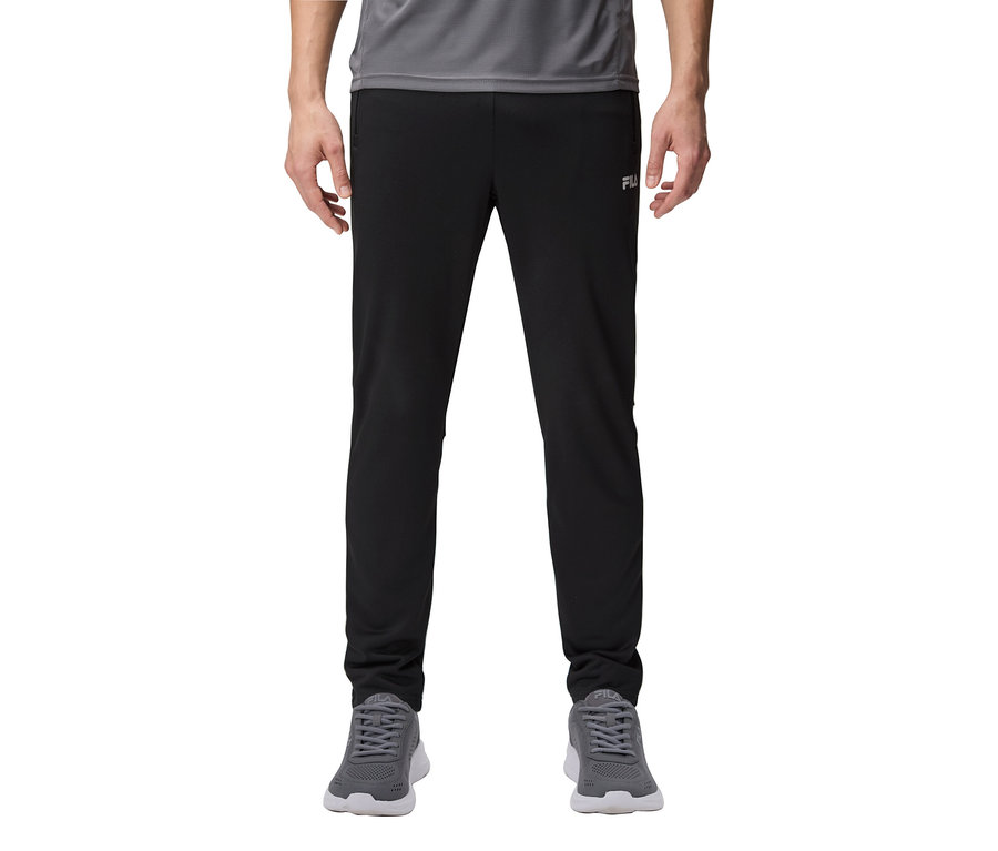 Un homme porte un pantalon de survêtement noir et des baskets grises.