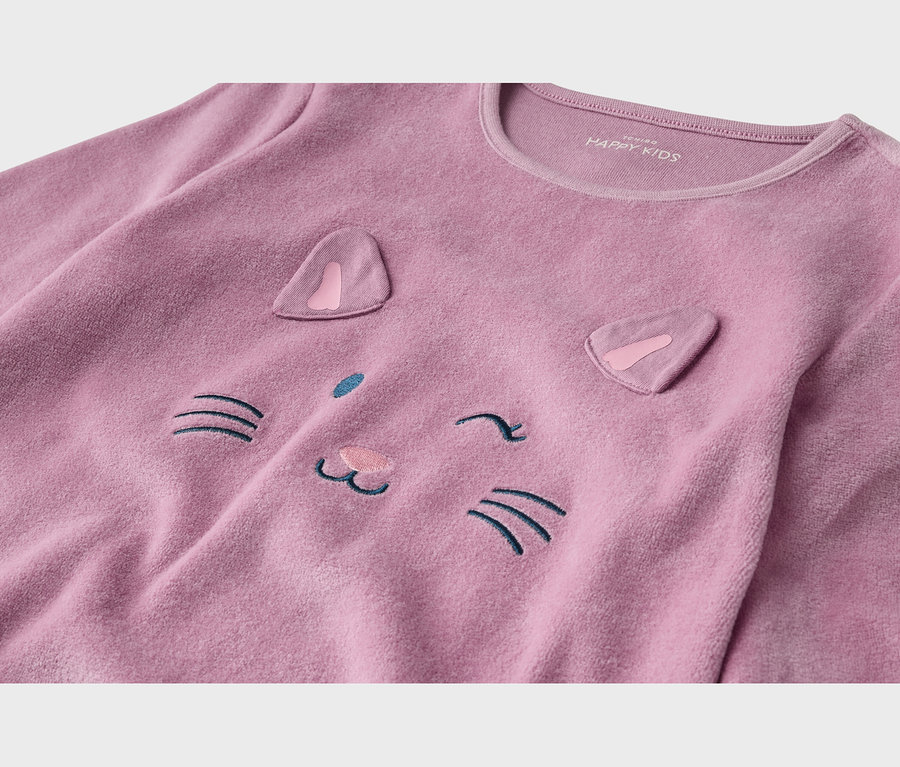 Gros plan d'un haut en polaire rose avec un motif de visage de chat. Il présente deux oreilles en tissu rose, des moustaches brodées bleu foncé, un nez rose clair et un œil qui cligne.