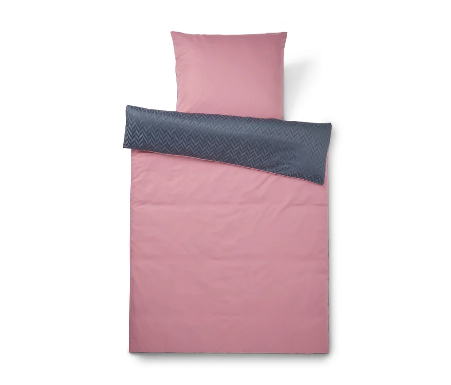 Parure de lit rose avec taie d'oreiller et housse de couette, dont le revers est gris foncé à motif chevrons.
