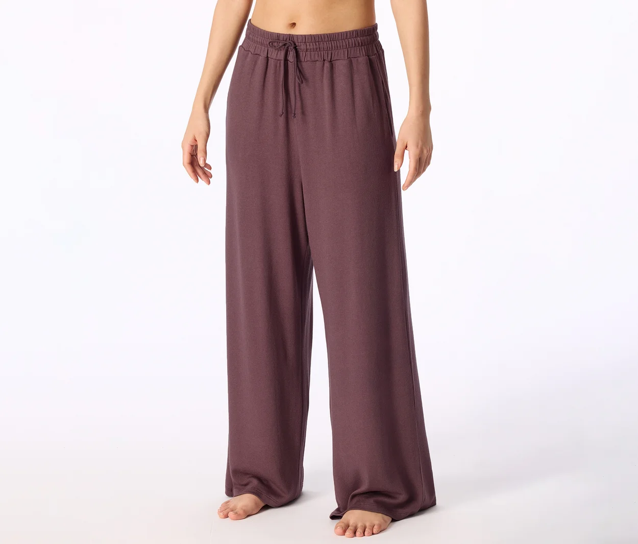 Personne pieds nus portant un pantalon large violet foncé avec un cordon de serrage à la taille.