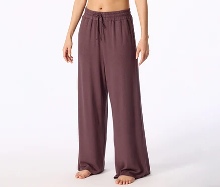 Personne pieds nus portant un pantalon large violet foncé avec un cordon de serrage à la taille.