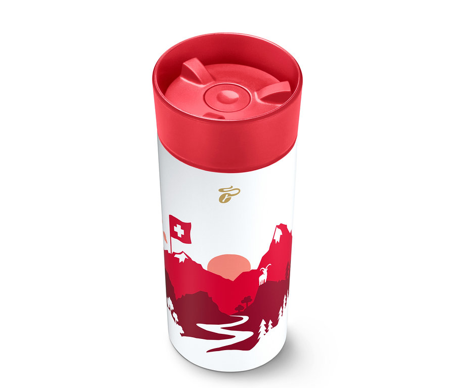 Mug thermique cylindrique blanc avec un couvercle rouge, orné d'un graphique rouge et blanc de montagnes, d'un soleil couchant, d'un drapeau suisse et d'une chèvre, avec un logo doré en haut.