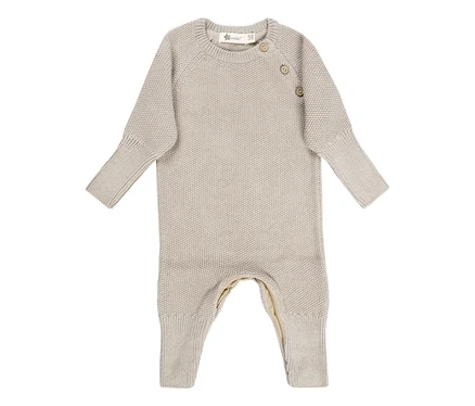 Grenouillère bébé tricotée beige avec manches et jambes longues, col rond et deux boutons sur l'épaule.