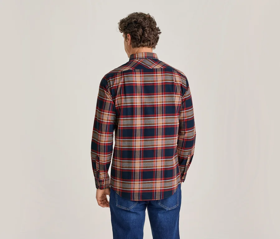 Homme de dos portant une chemise à carreaux bleu foncé, rouge, orange et blanc, et un jean bleu.