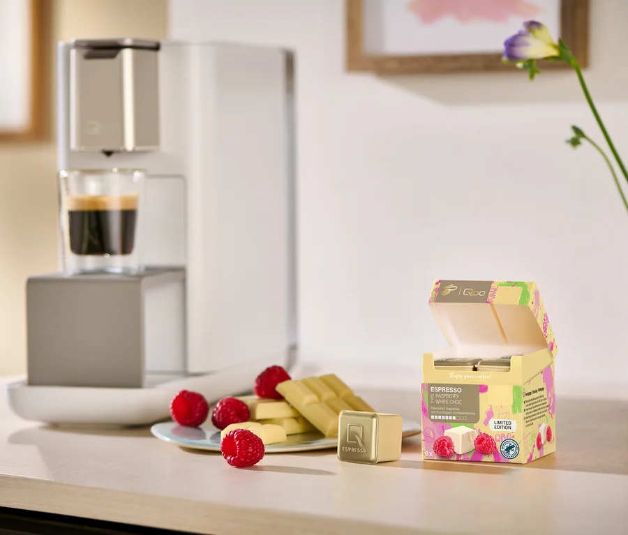 Expresso et chocolat blanc avec framboises sur une table à côté d'une machine à café.