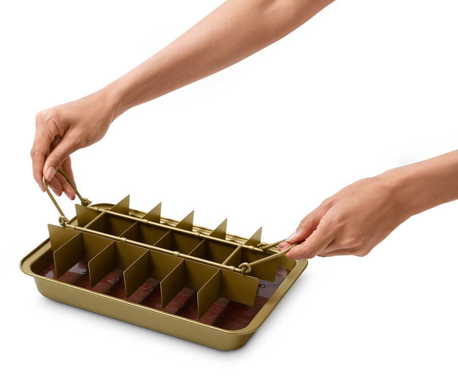 Des mains tiennent un moule à brownie avec un mélange brun à l'intérieur.