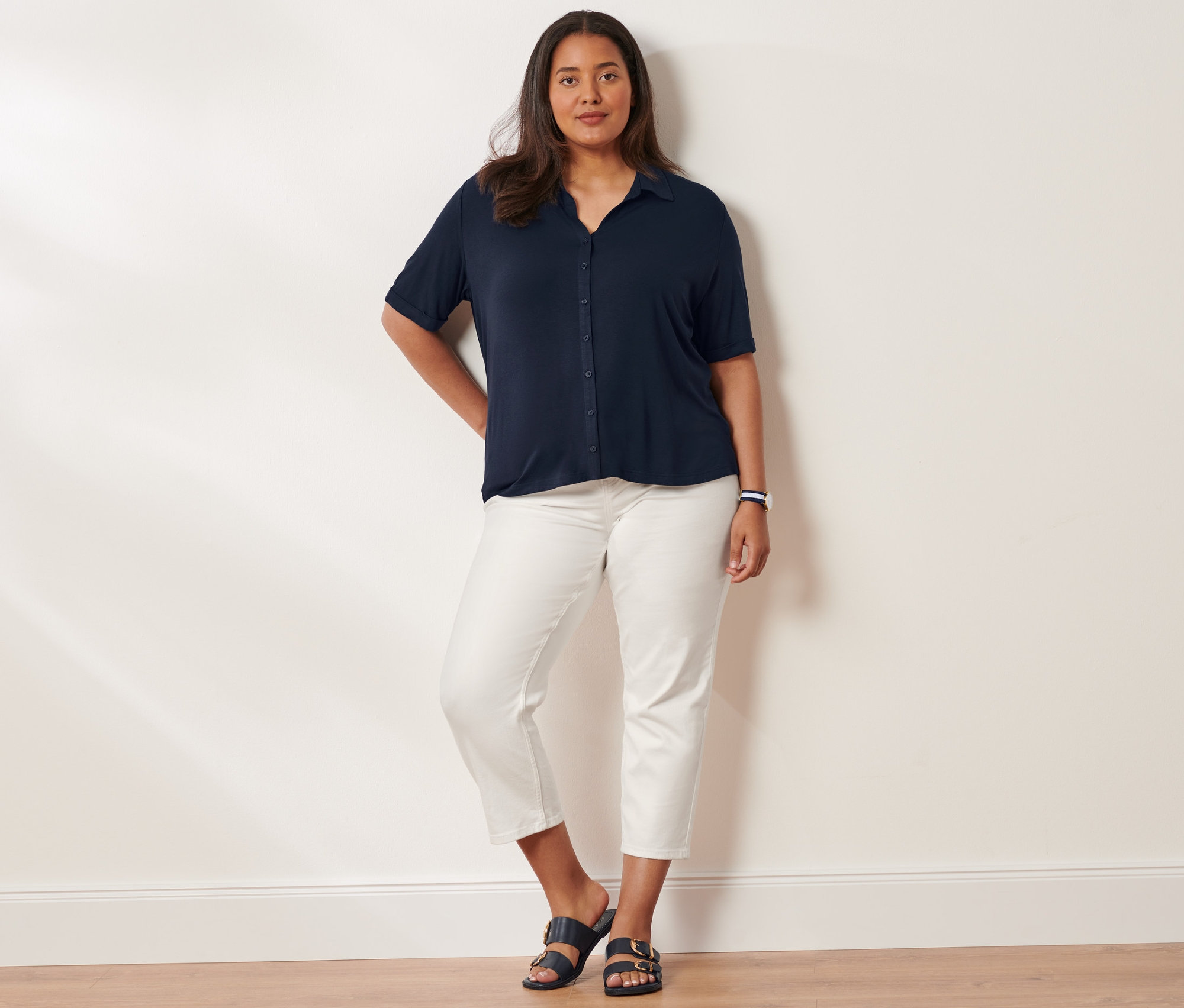 Une femme pose, portant une blouse avec patte de boutonnage, un jean slim et des sandales à brides. Elle porte une montre-bracelet à quartz en acier inoxydable.