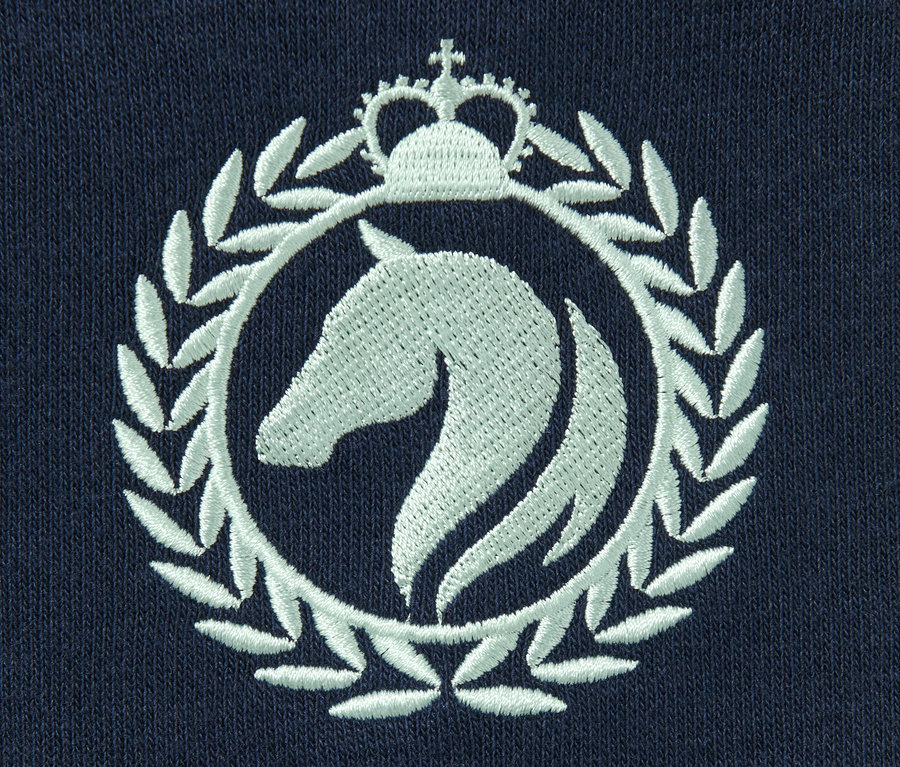 Détail d'un sweat-shirt bleu marine avec un logo de cheval blanc brodé dans un cercle avec une couronne.