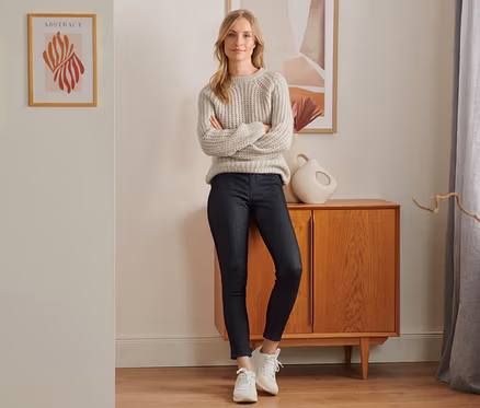 Une femme se tient debout, les bras croisés, portant un legging doublé à l’aspect jean, denim noir.