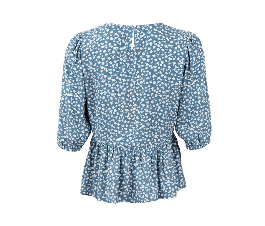 Blouse avec froufrou bleue à motifs floraux blancs.