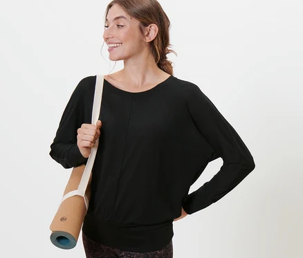 Femme tenant un tapis de yoga et portant un t-shirt de sport et de yoga noir.