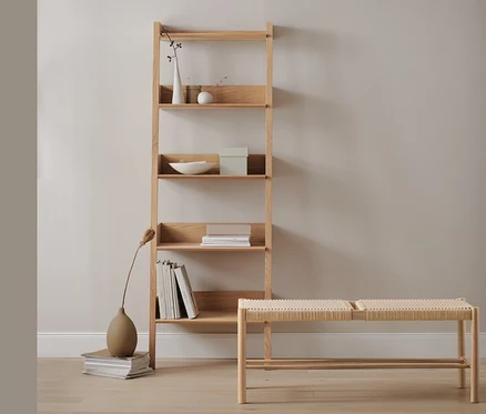 Un rayonnage échelle en chêne avec des décorations et des livres à côté d'un banc avec matière tressée.