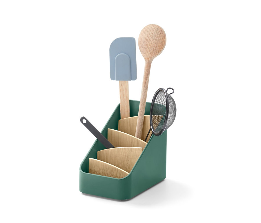 Dans un support pour ustensiles vert se trouvent une cuillère en bois, une passoire et une spatule.