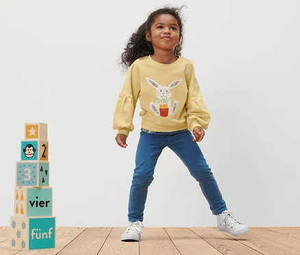 Fillette posant dans un sweat-shirt pour tout-petit avec un imprimé de lapin.