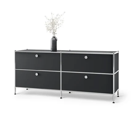 Meuble bas en métal « CN3 » noir avec 4 tiroirs et un vase avec des fleurs blanches sur le dessus.