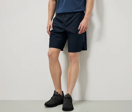 Homme debout portant un short de sport.