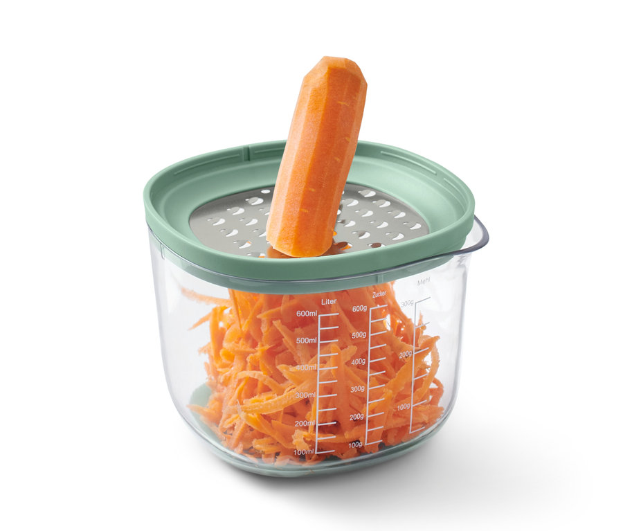 Carotte sur une râpe au-dessus d'un récipient contenant des carottes râpées de l'ensemble de cuisson et de préparation.