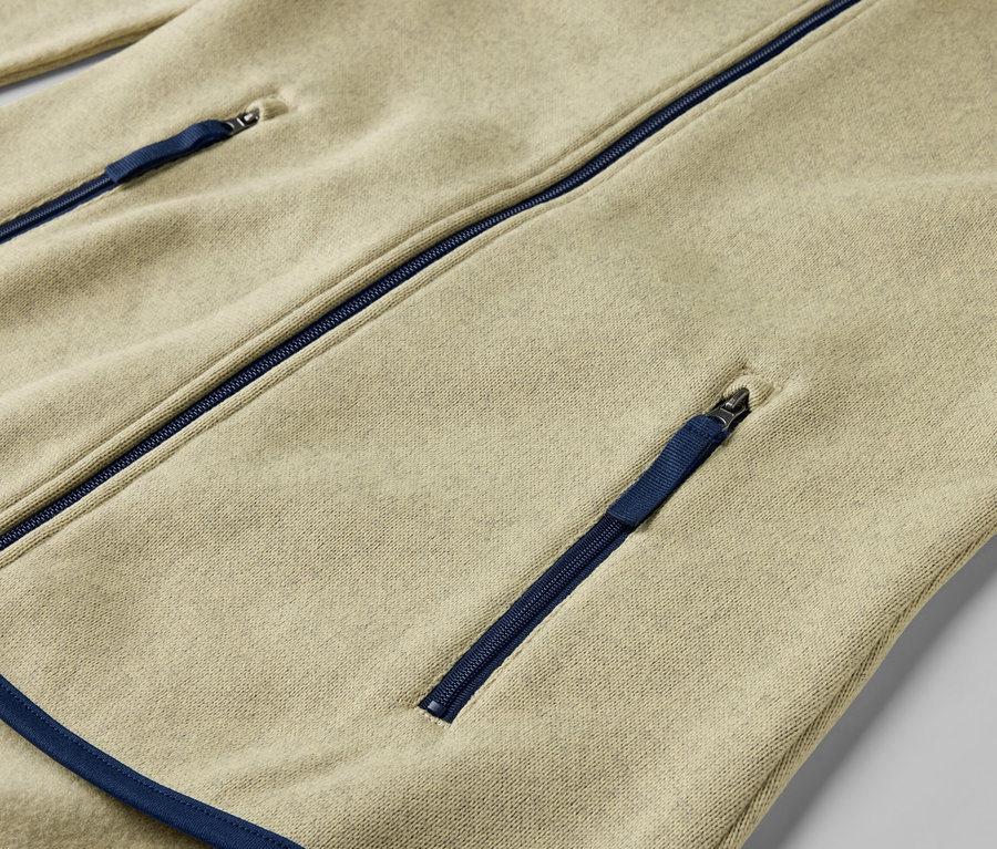 Gros plan sur une veste en polaire tricotée jaune avec des fermetures éclair bleues.