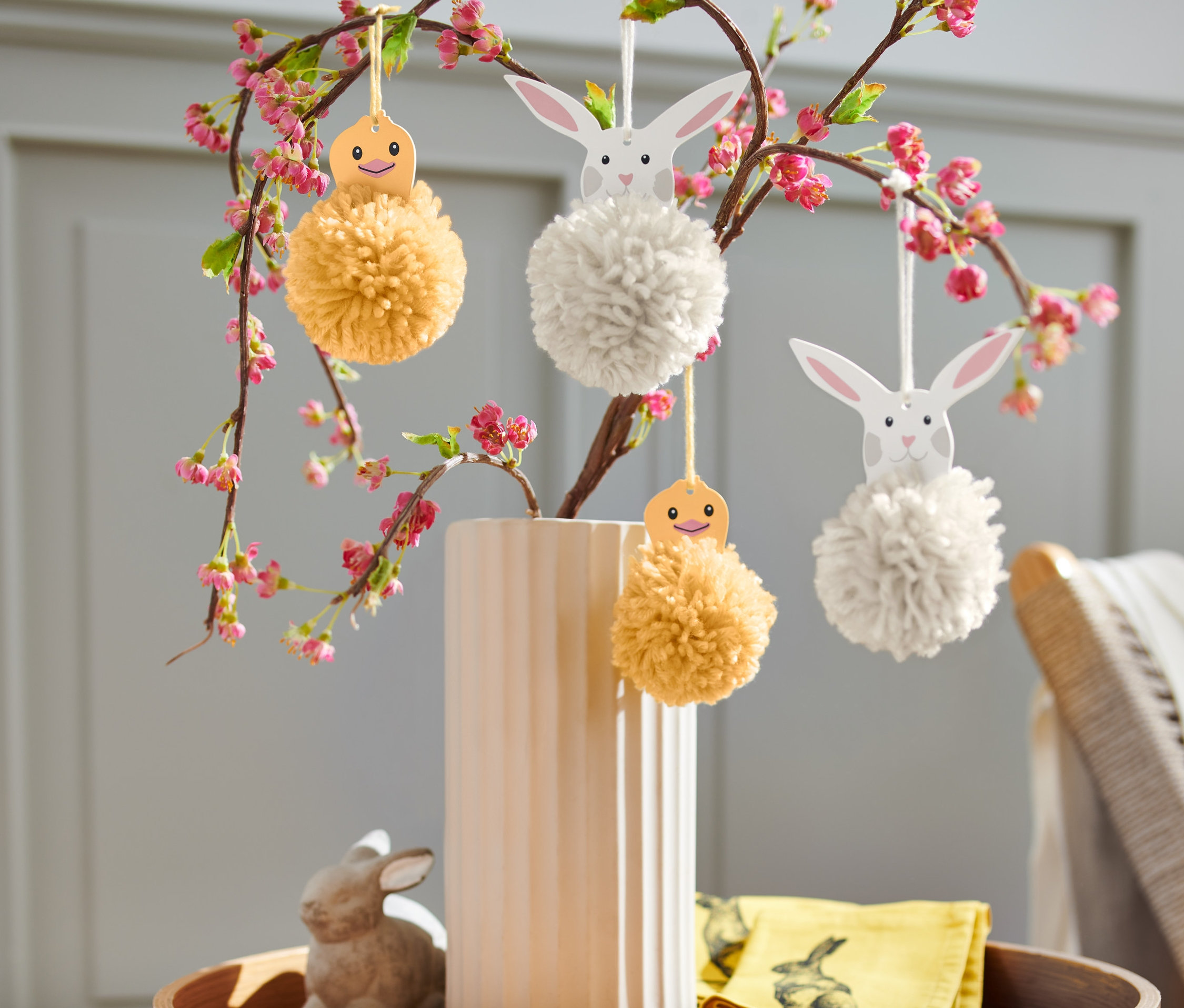 Vase de fleurs avec des branches et des décorations de kit de construction pour pompons de Pâques.