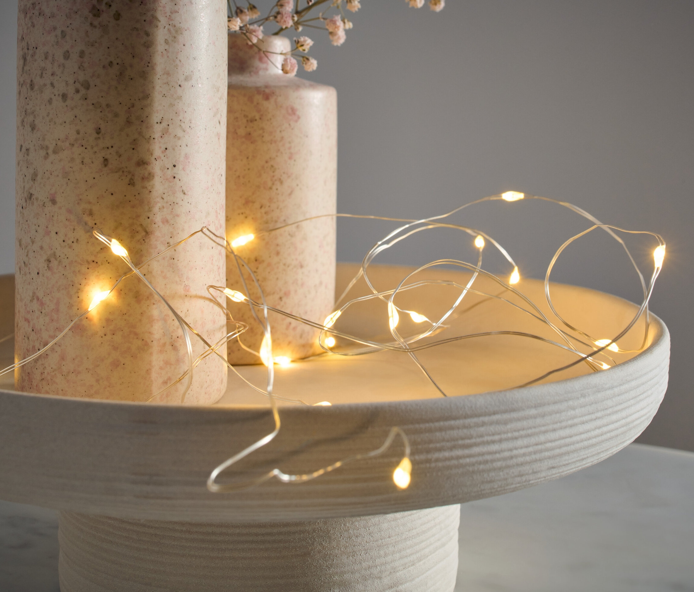 Micro-guirlande lumineuse à LED, gouttes, posée sur un plateau décoratif à côté de deux vases.