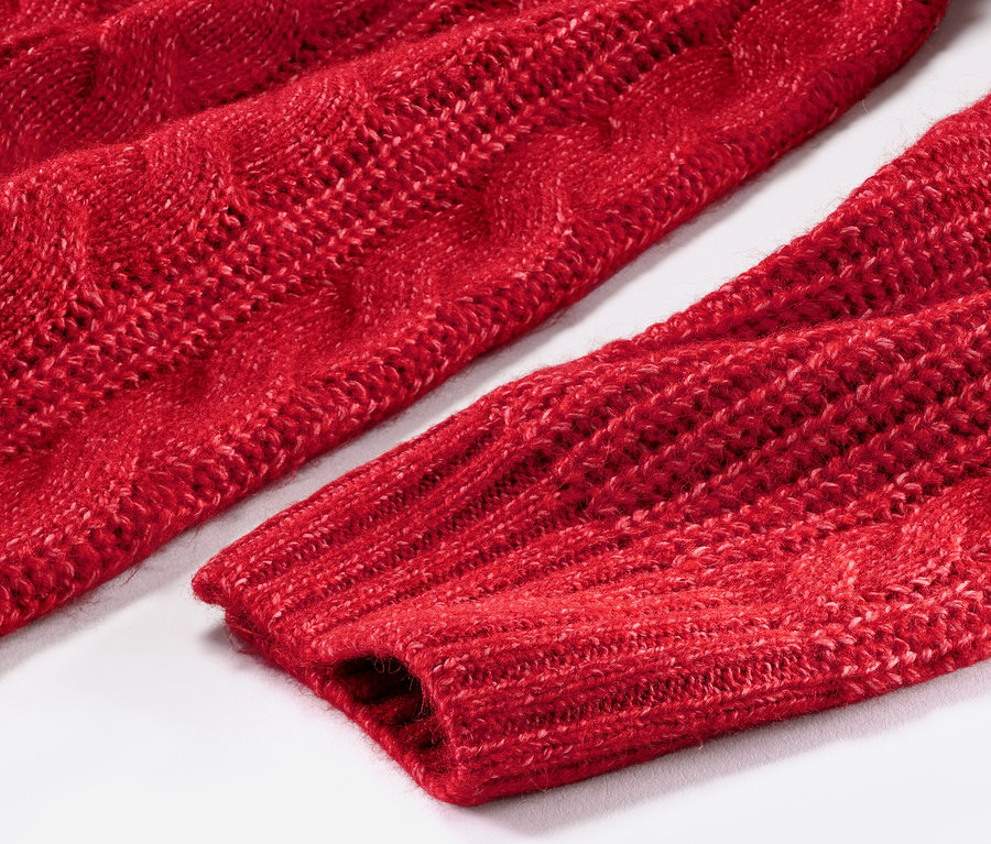 Gros plan sur un long pull en maille rouge avec torsades.