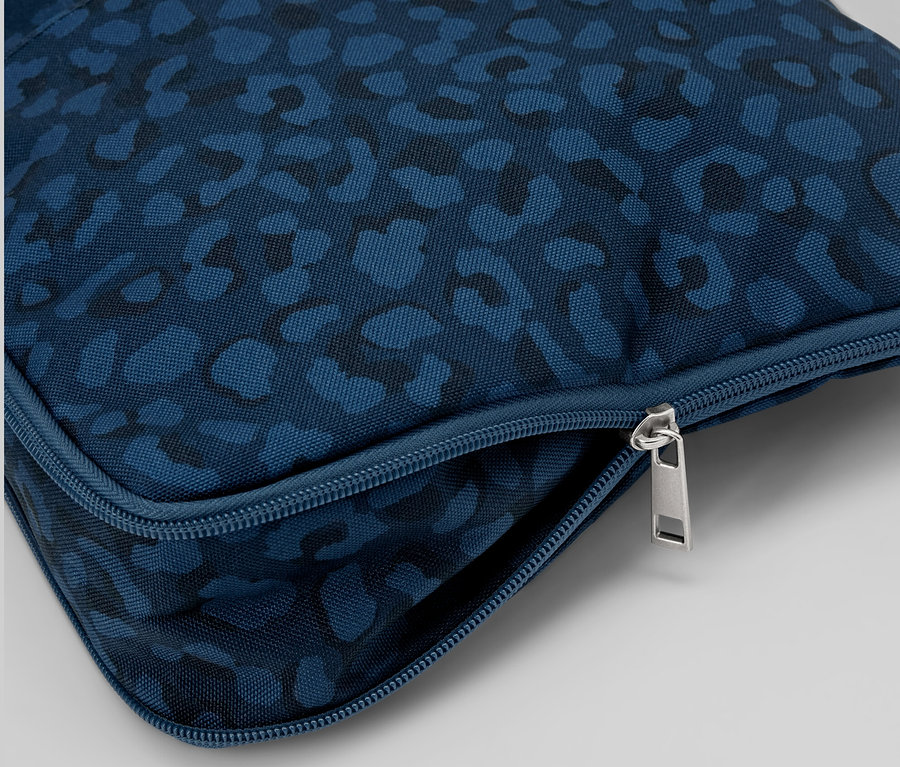 Gros plan d'un sac à bandoulière de sécurité bleu à motifs avec fermeture éclair argentée.