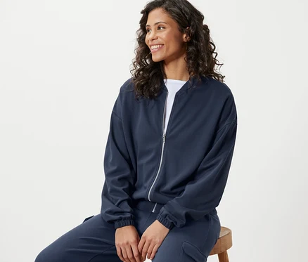 Femme assise portant une veste de survêtement bleue.