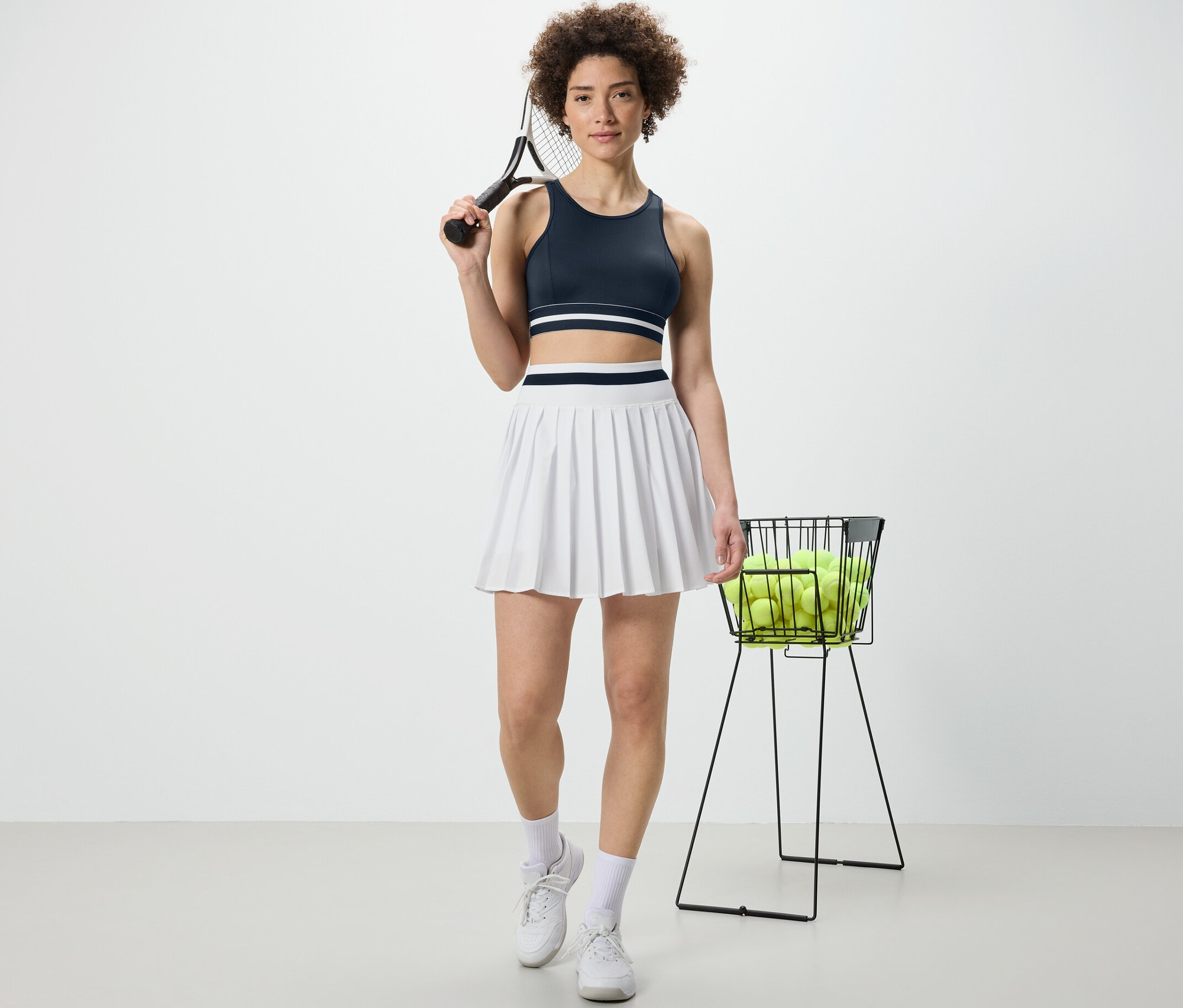 Femme tenant une raquette de tennis et portant un bustier de sport bleu « Crop Top ».