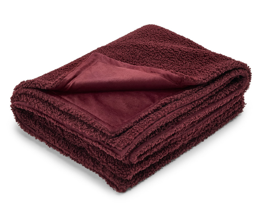 Couverture bordeaux pliée avec une texture en peluche d'un côté et une texture lisse de l'autre.