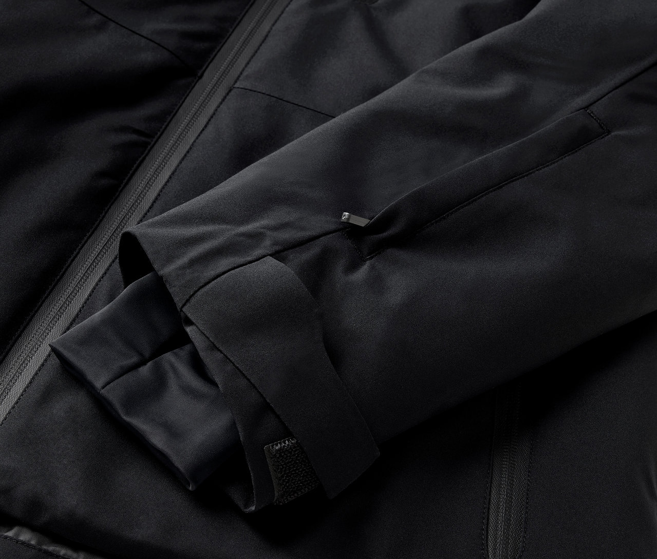Gros plan sur une veste noire avec une manche et une poche zippée.
