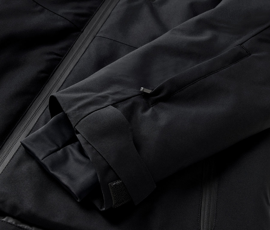 Gros plan sur une veste noire avec une manche et une poche zippée.