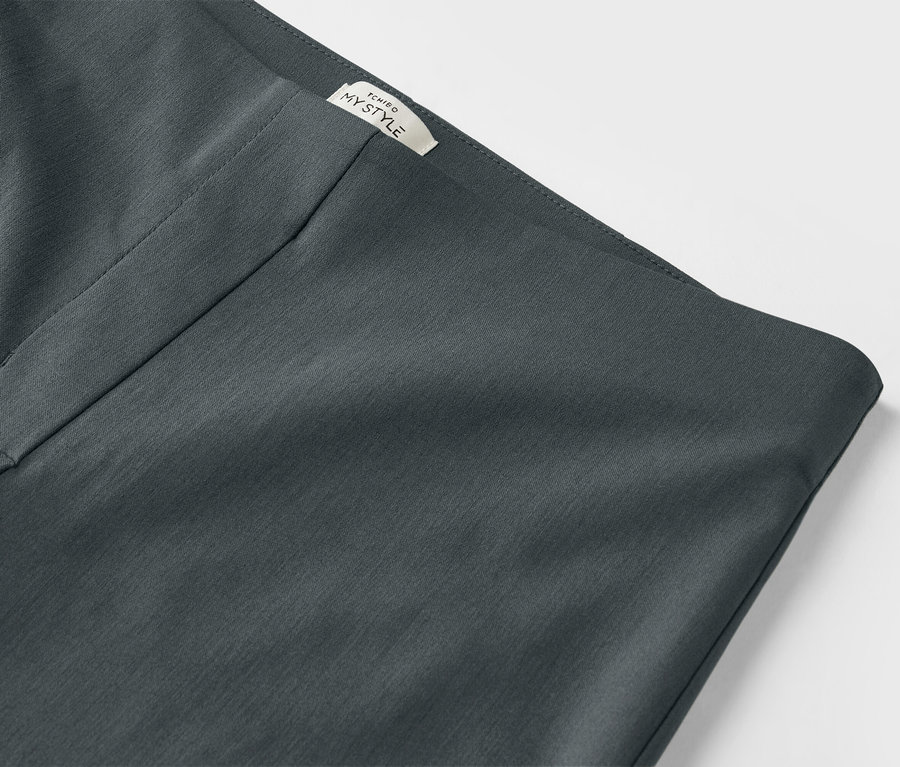 Détail d'un pantalon stretch vert foncé.