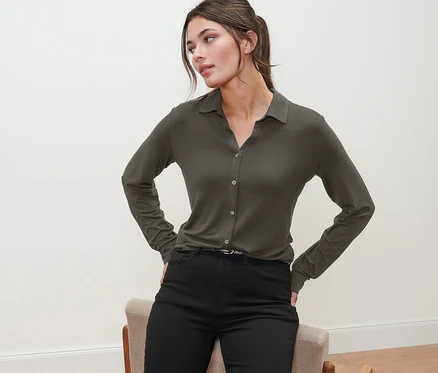 Femme posant en blouse olive avec patte de boutonnage et pantalon noir.