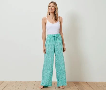 Une femme debout portant un débardeur blanc et un pantalon relax.