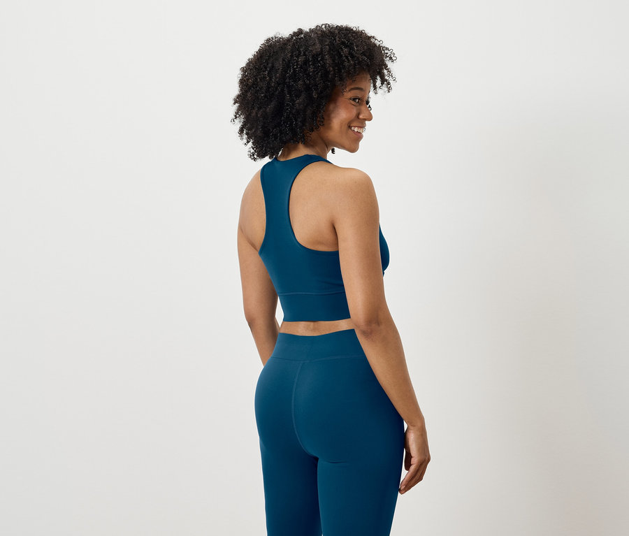 Femme regardant par-dessus son épaule, vêtue d'un ensemble de sport bleu.