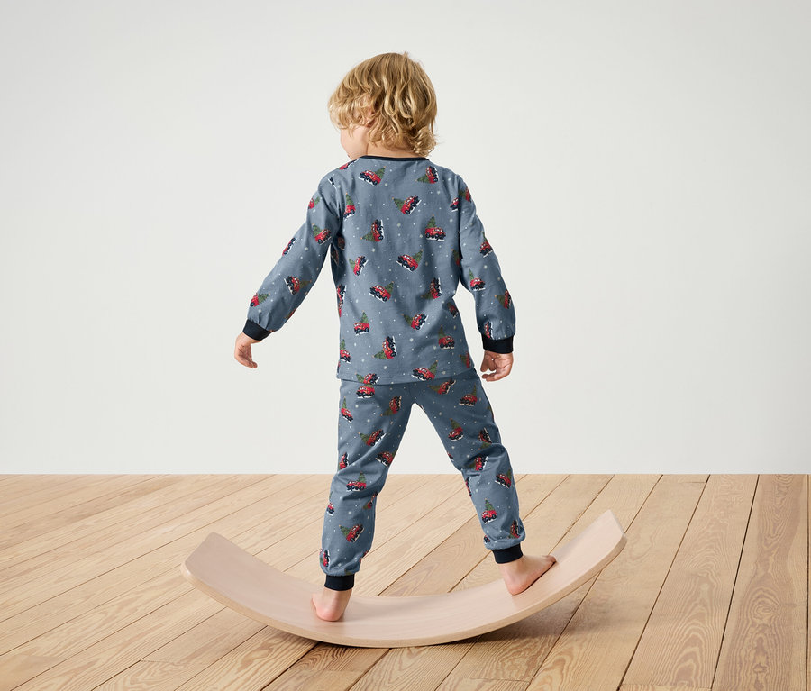 Garçon en pyjama de Noël debout sur une planche d'équilibre en bois.