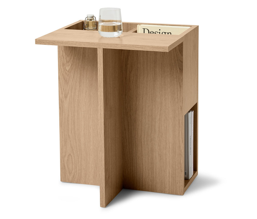 Table d'appoint en bois clair avec un verre d'eau, une lampe et un magazine.