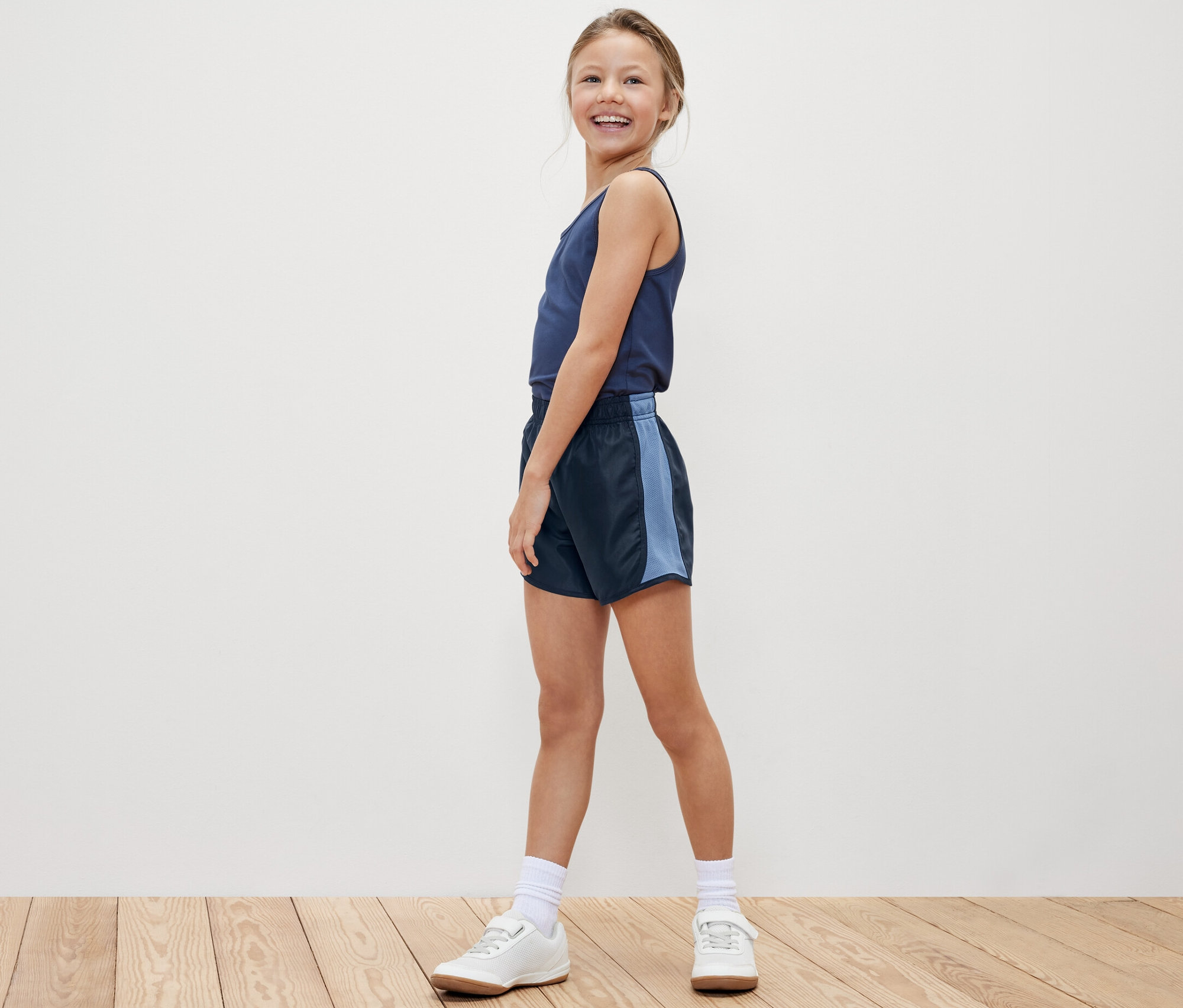 Fillette souriante posant en débardeur et un des 2 shorts de sport pour enfants.