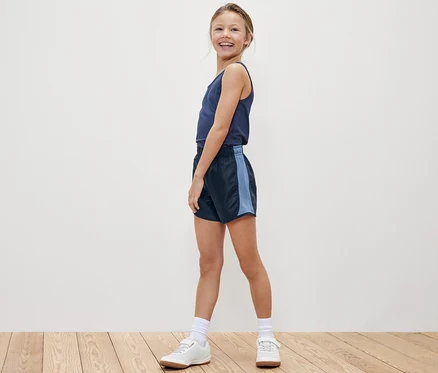 Fillette souriante posant en débardeur et un des 2 shorts de sport pour enfants.