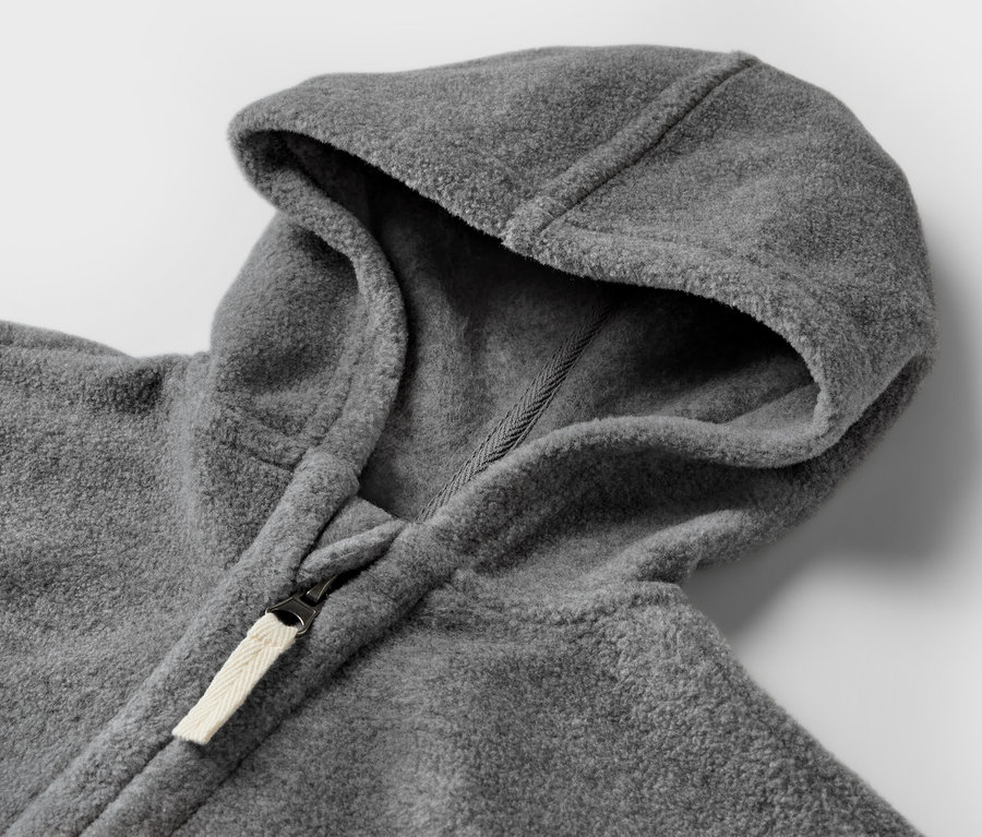 Gros plan sur une veste en polaire grise pour bébé avec capuche et fermeture éclair.