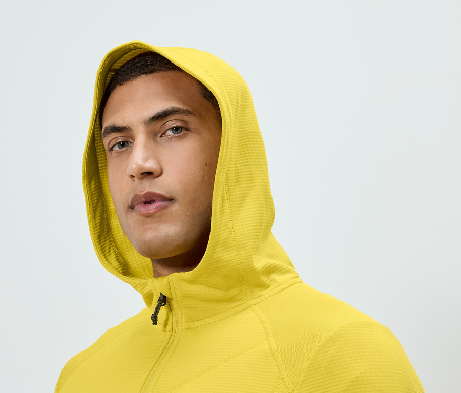 Portrait d'un homme portant un sweat à capuche jaune zippé.
