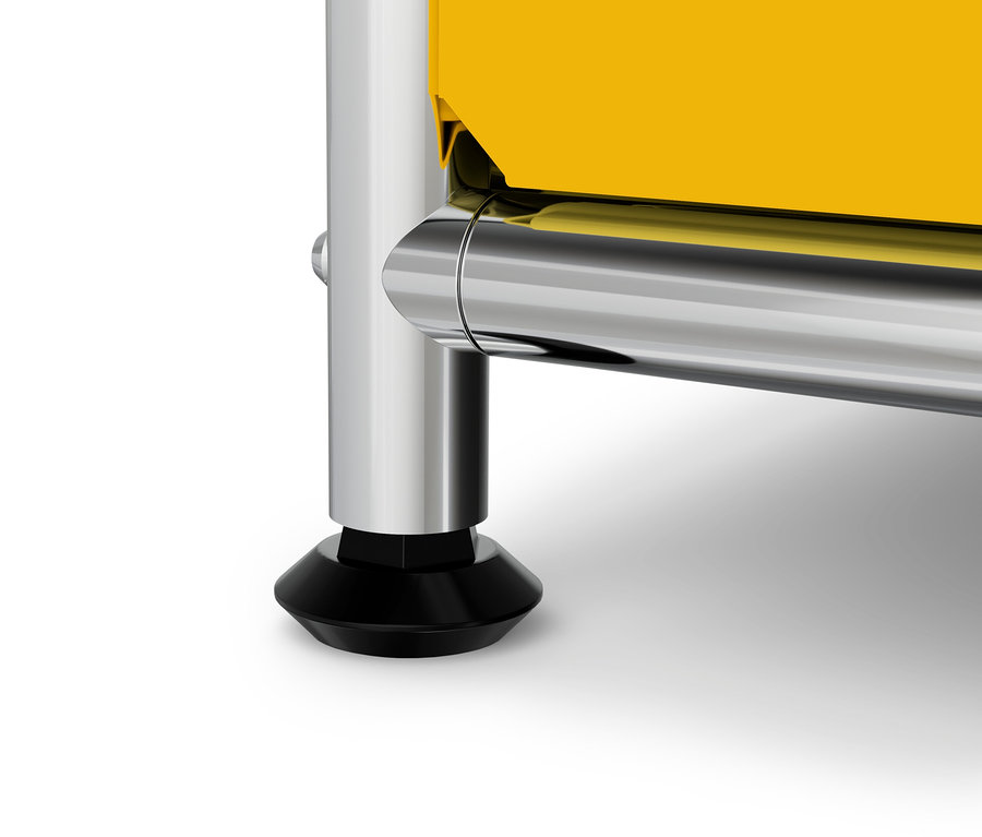 Détail d'un meuble jaune avec un pied chromé et un embout noir.