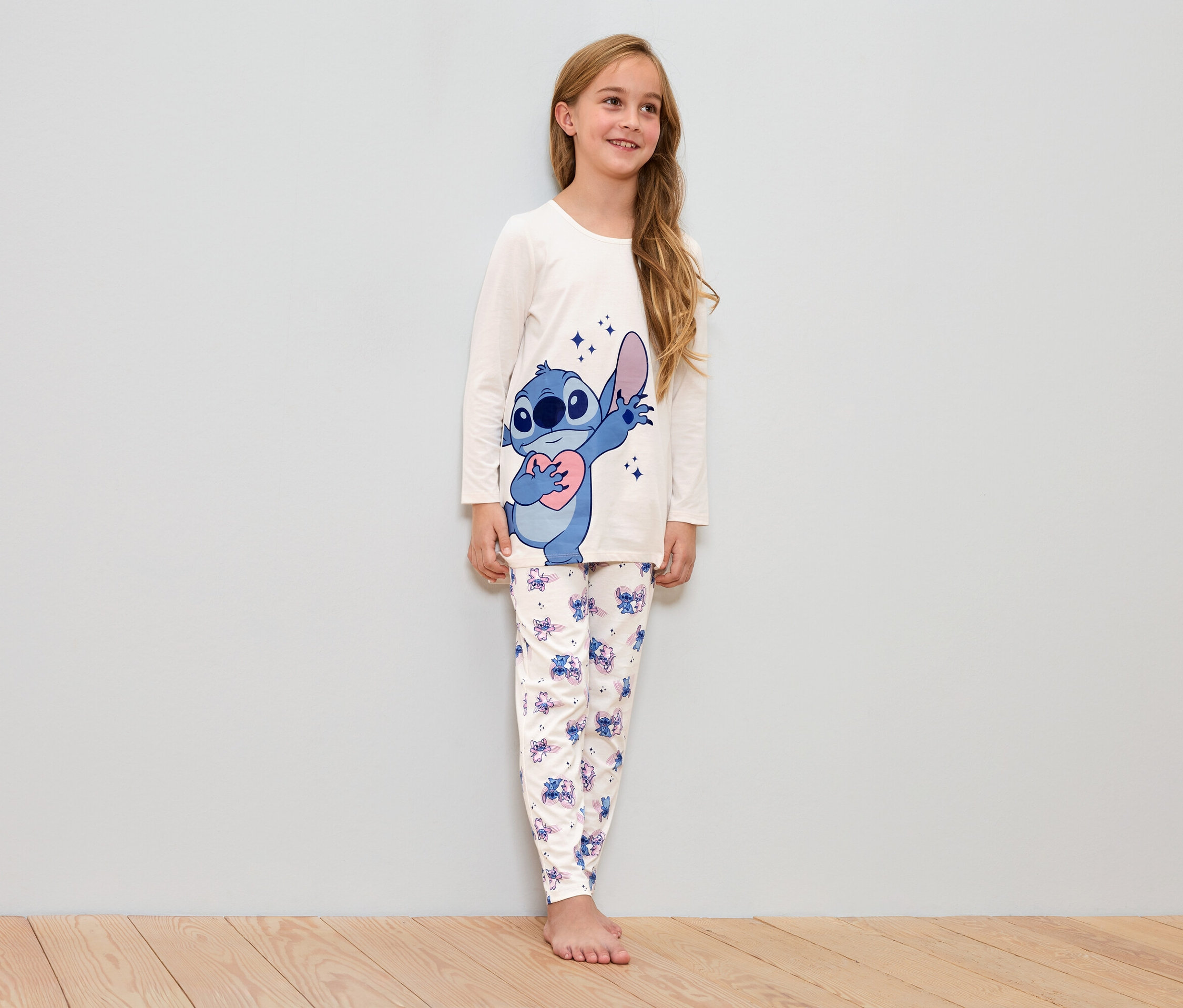 Fille portant un pyjama blanc avec un motif Stitch.