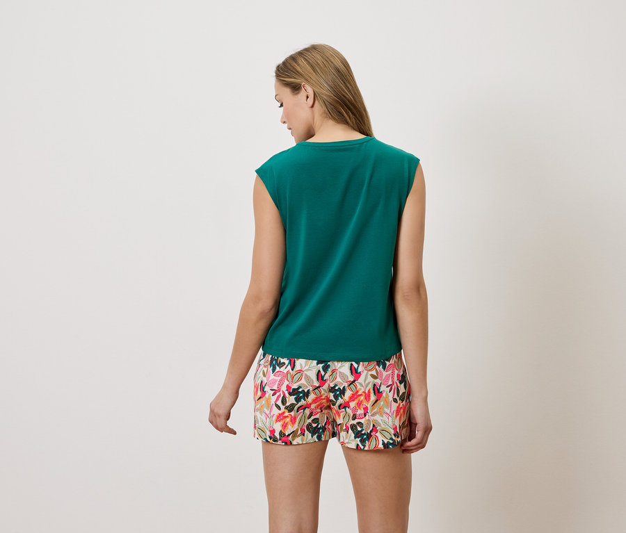 Vue arrière d'une femme blonde portant un haut vert sans manches et un short à fleurs.