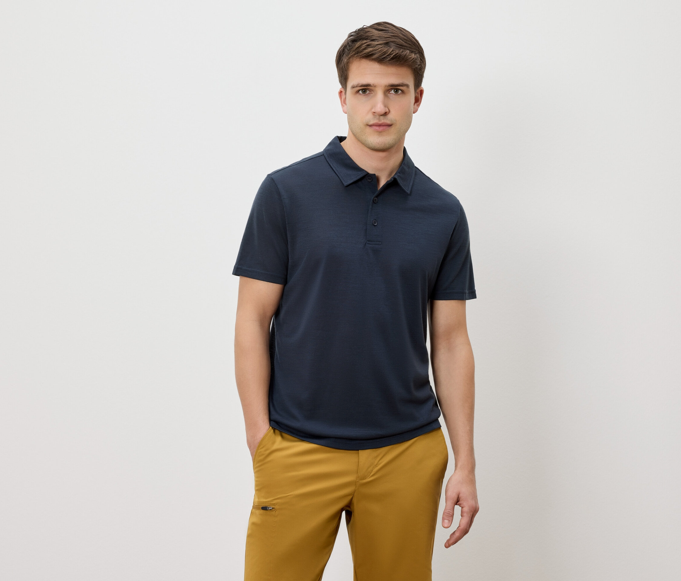 Homme portant un polo bleu marine et un pantalon jaune sur fond blanc.