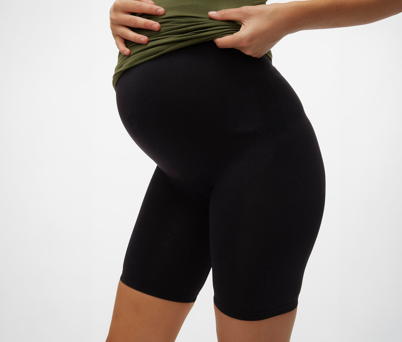 Femme enceinte portant un t-shirt vert olive et un Skinny Short noir MAMALICIOUS «
MLTIA JEANNE
».