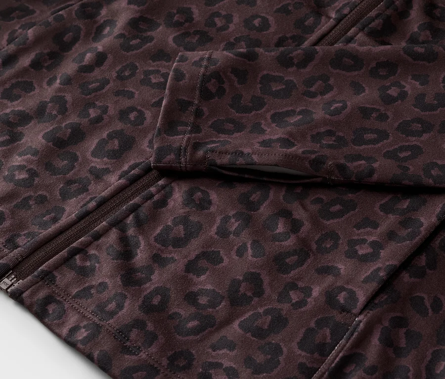 Gros plan sur une veste marron foncé partiellement ouverte avec un motif léopard noir et une fermeture éclair.