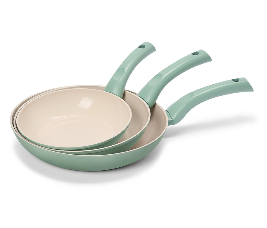 Trois poêles à frire vertes avec des surfaces intérieures couleur crème sont empilées.